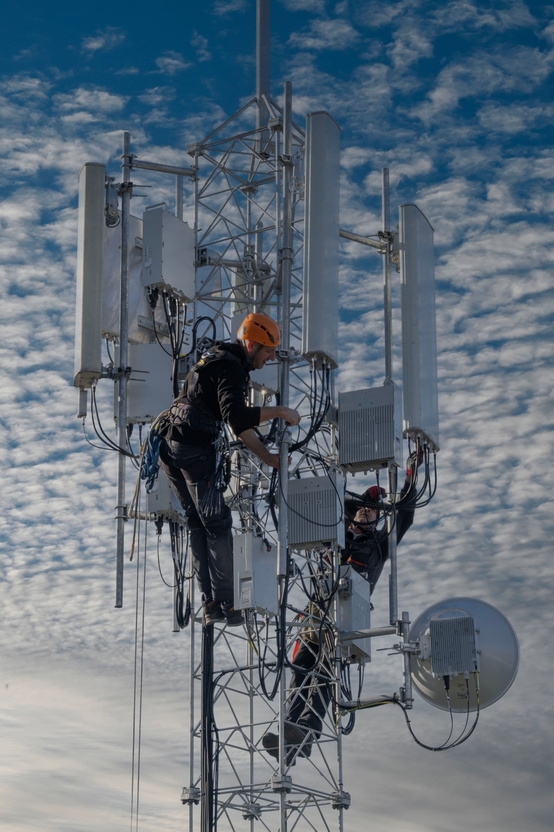 Field technicians installing equipment atop a communications tower