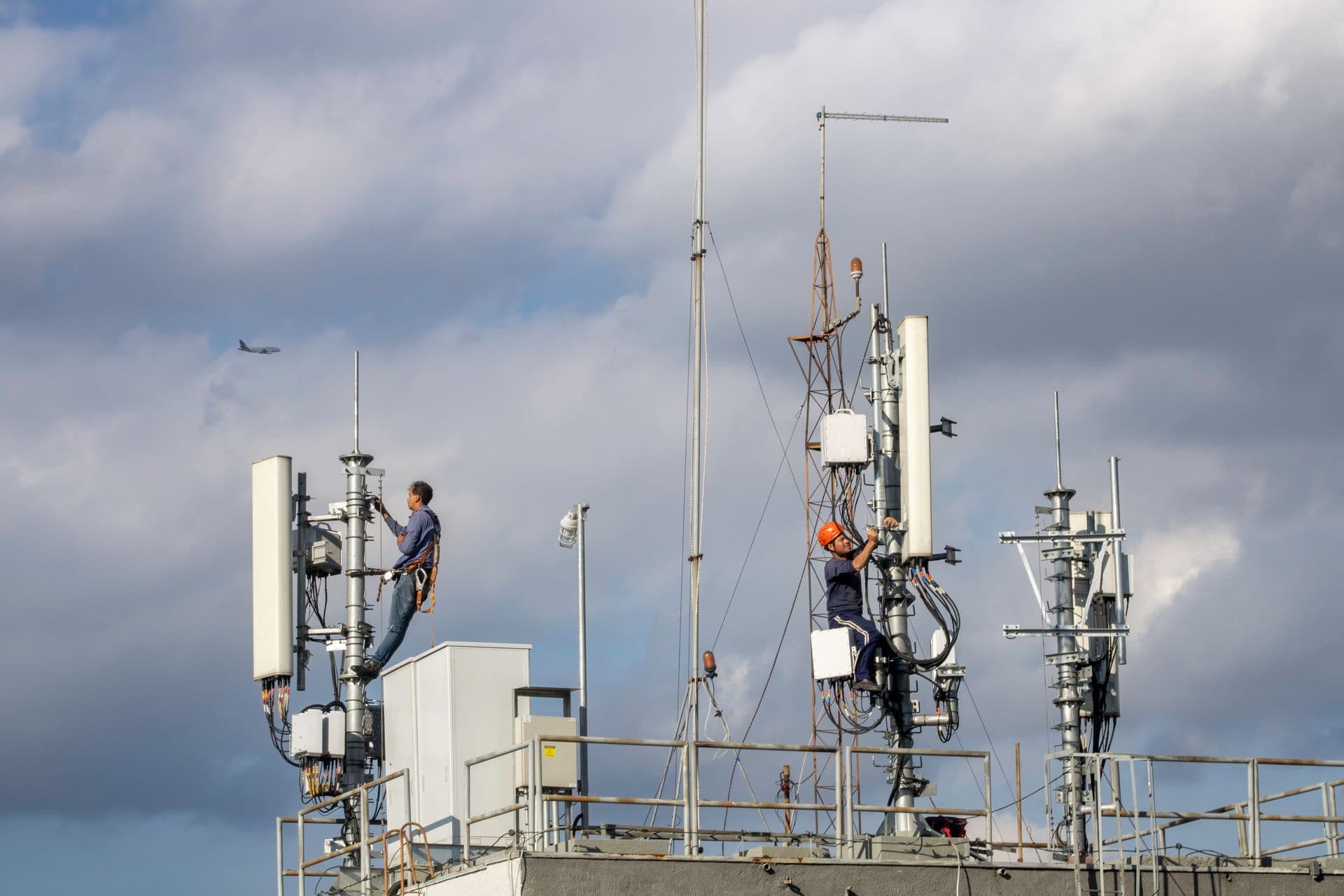 Technicians servicing rooftop communications antennas
